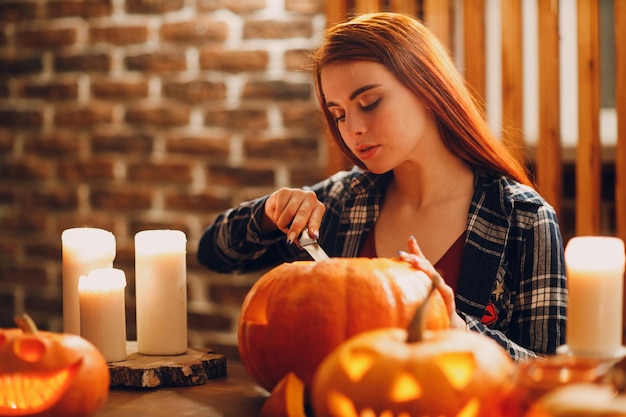 Mujer joven haciendo calabaza de Halloween Jackolantern Manos femeninas cortando calabazas con un cuchillo
