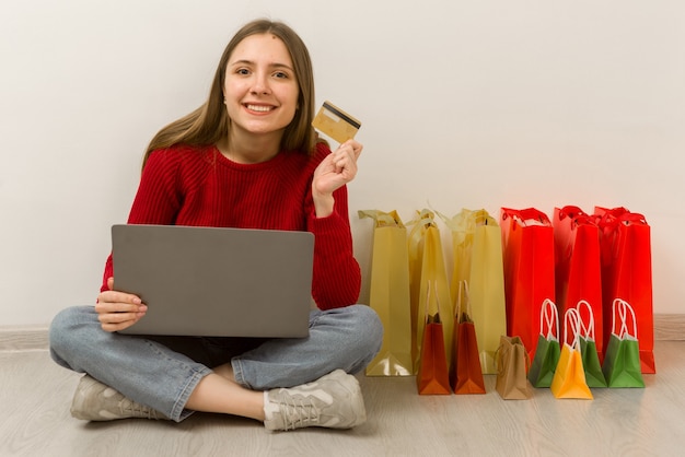 Mujer joven haciendo compras en línea en casa usando la computadora portátil. Cliente satisfecho feliz con la compra