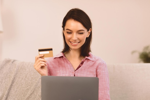 Mujer joven haciendo compras sentada en el sofá