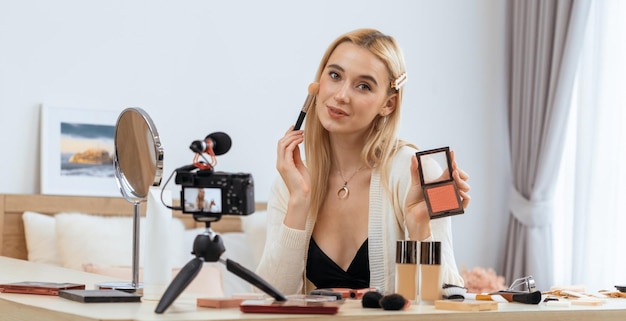 Mujer joven haciendo contenido de video tutorial de belleza y cosmética para las redes sociales Blogger de belleza sonríe a la cámara mientras muestra cómo cuidar la belleza a la audiencia o seguidores Panorama Blithe