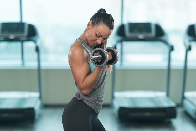 Mujer joven haciendo ejercicio de bíceps con pesas