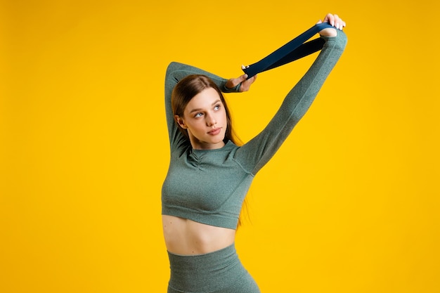 Mujer joven haciendo ejercicio contra un fondo amarillo