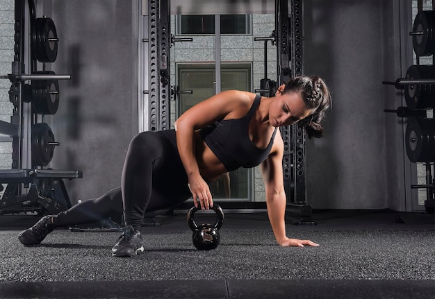 Foto mujer joven haciendo ejercicio con kettlebell en el gimnasio