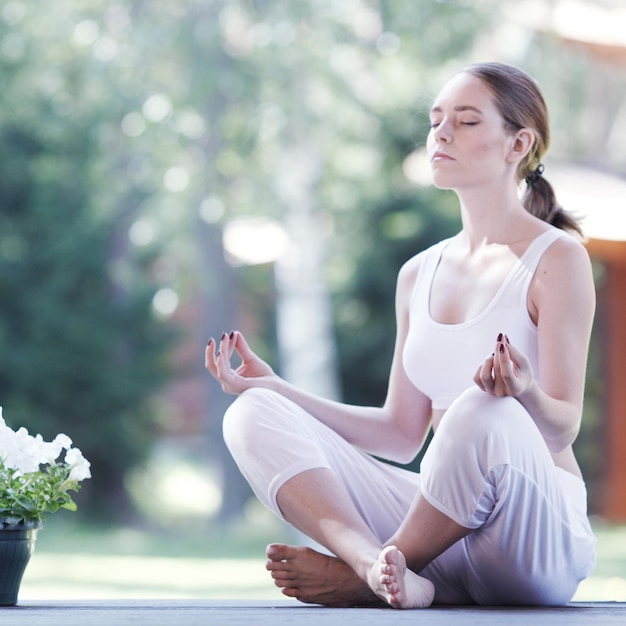 Mujer joven haciendo ejercicio de loto de yoga al aire libre