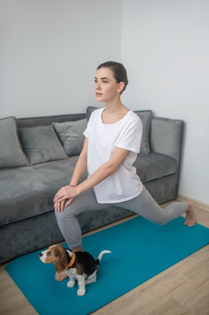 Una mujer joven haciendo ejercicio mientras su cachorro sentado junto a ella