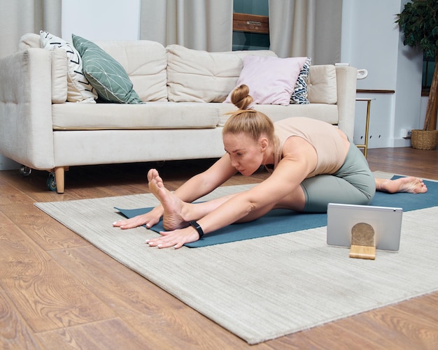 Foto mujer joven haciendo ejercicio de yoga en una habitación en casa