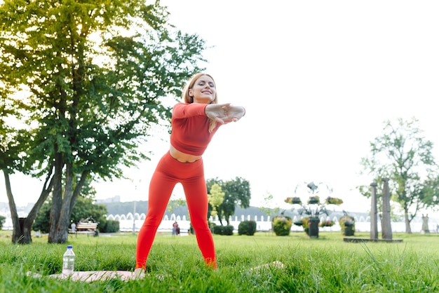 Mujer joven haciendo ejercicio de yoga en el parque verde