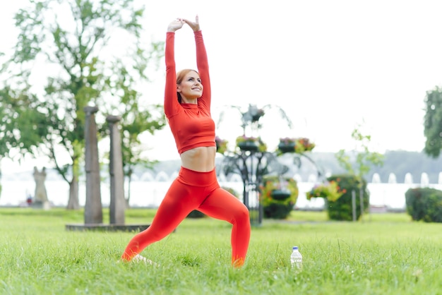 Mujer joven haciendo ejercicio de yoga en el parque verde