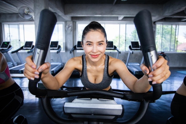 Mujer joven haciendo ejercicios cardiovasculares en clase de spinning con máquinas de ejercicio en el gimnasio.