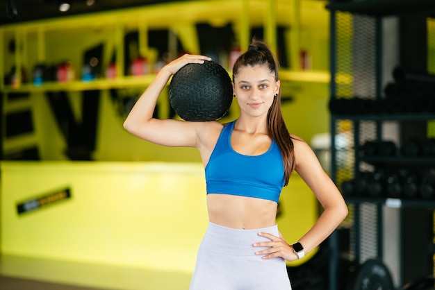 Mujer joven haciendo ejercicios con pelota en el gimnasio.