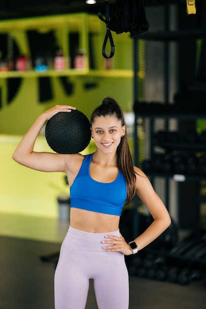 Mujer joven haciendo ejercicios con pelota en el gimnasio.