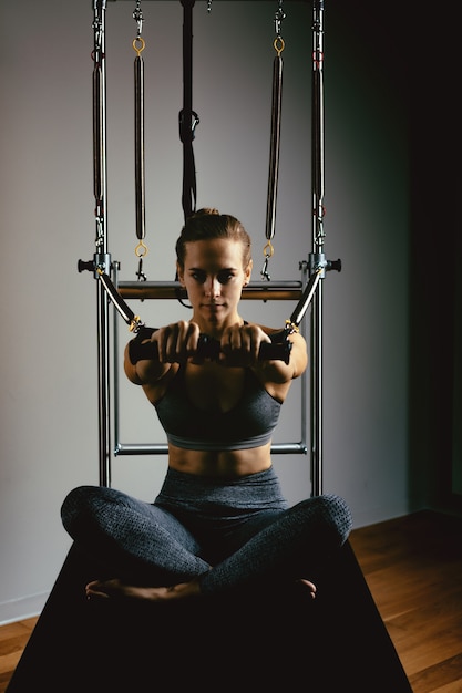 Mujer joven haciendo ejercicios de pilates con una cama reformadora