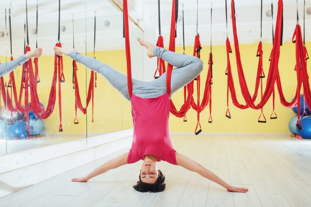 Mujer joven haciendo ejercicios de yoga antigravedad