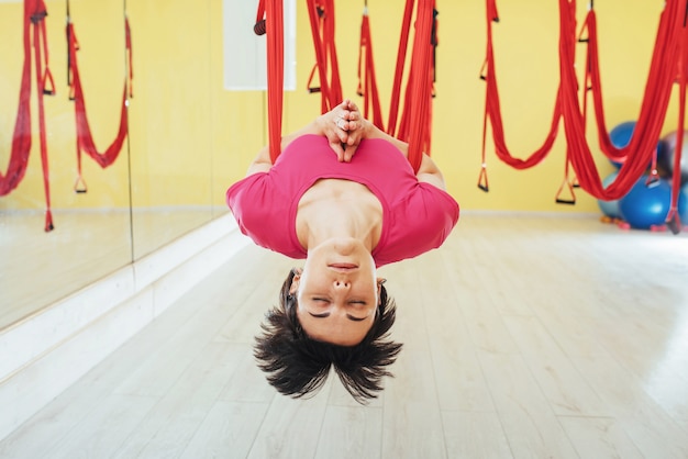 Mujer joven haciendo ejercicios de yoga antigravedad