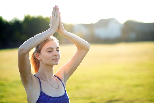 Mujer joven haciendo ejercicios de yoga fitness en cálido día de verano