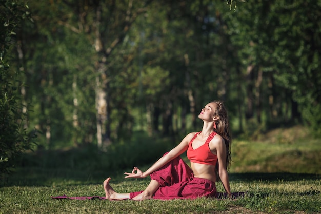 Mujer joven haciendo ejercicios de yoga en el parque de la ciudad de verano