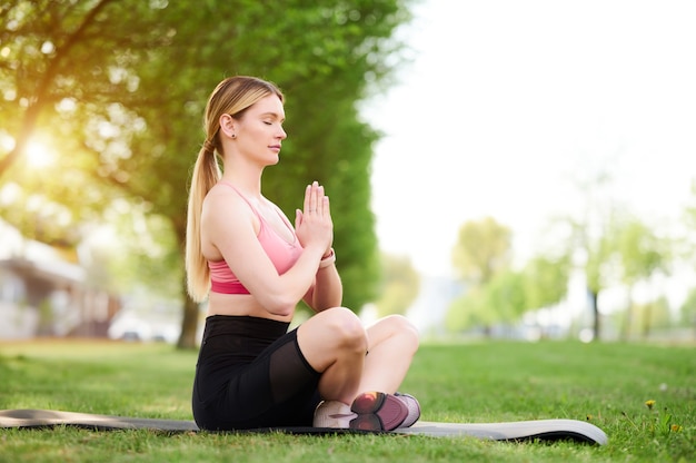 Mujer joven haciendo ejercicios de yoga en el parque