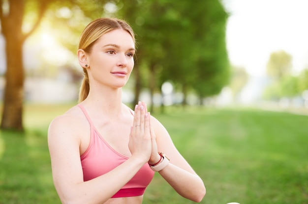 Mujer joven haciendo ejercicios de yoga en el parque