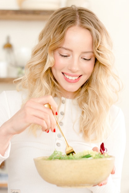 Mujer joven haciendo una ensalada en casa