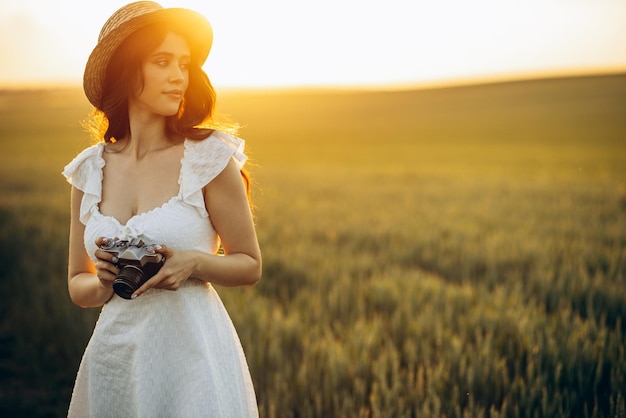 Mujer joven haciendo fotos con cámara en el campo