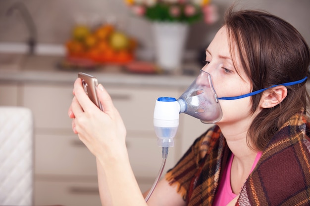 Mujer joven haciendo inhalación con un nebulizador en casa