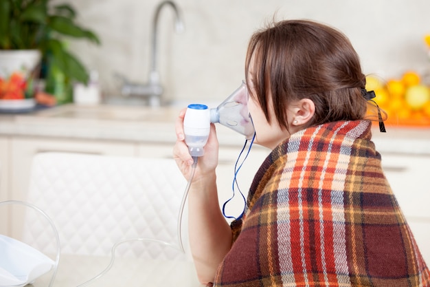 Foto mujer joven haciendo inhalación con un nebulizador en casa
