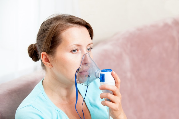 Mujer joven haciendo inhalación con un nebulizador en casa