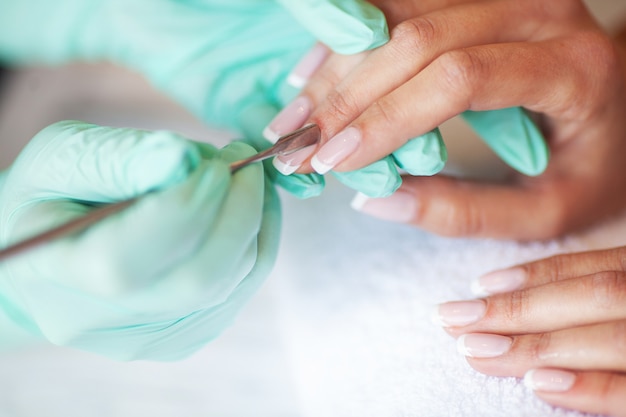 Mujer joven haciendo manicura en el salón