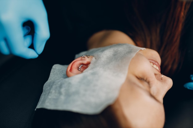 Mujer joven haciendo piercing en la oreja en el salón de belleza