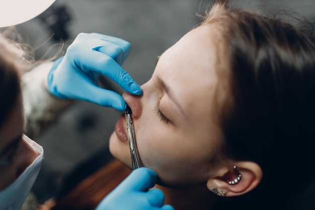 Mujer joven haciendo piercing en el salón de belleza