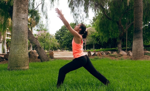 Mujer joven haciendo una postura de yoga en la hierba