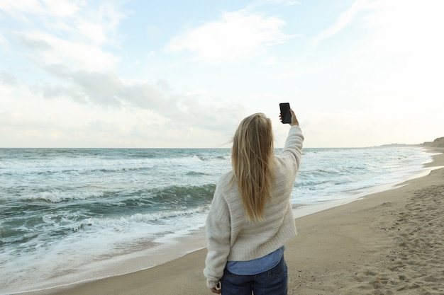 Mujer joven haciendo selfie en la playa de arena