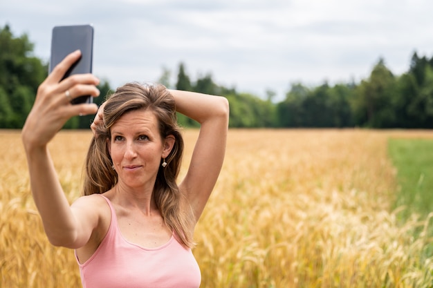 Mujer joven haciendo selfies con su teléfono móvil afuera