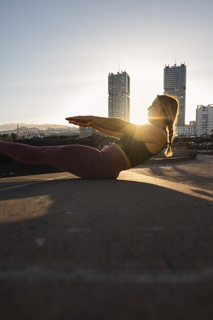 Foto mujer joven haciendo sentadillas con edificios al fondo