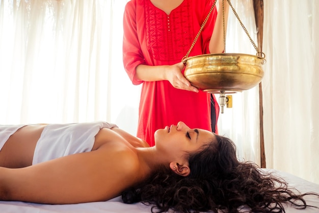 Mujer joven haciendo tratamiento tradicional indio de atención médica en el centro de constitución del cuerpo de Ayurveda