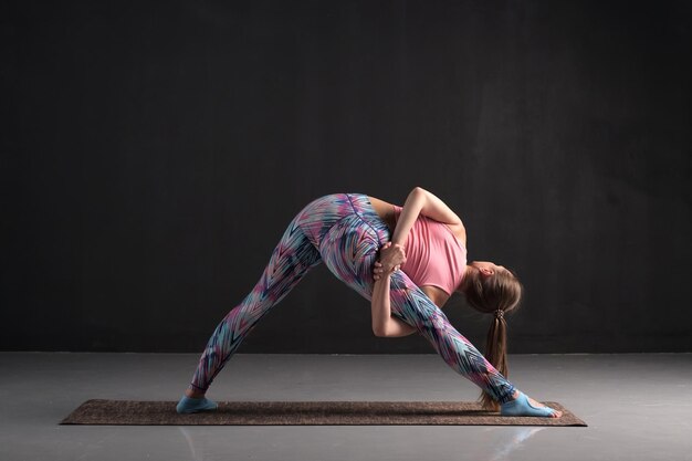 Mujer joven haciendo una variación de la pose de yoga Trikonasana