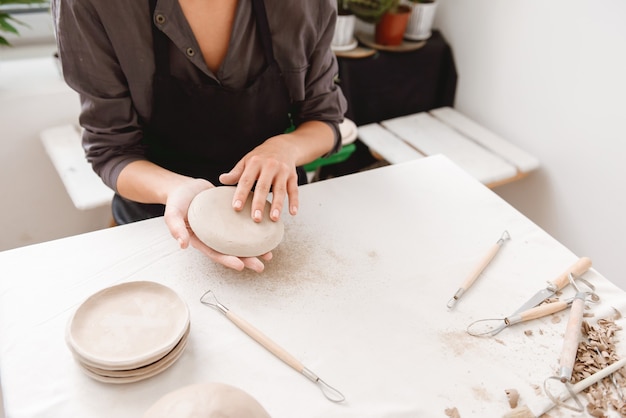 Mujer joven haciendo vasijas de barro en el taller de alfarería