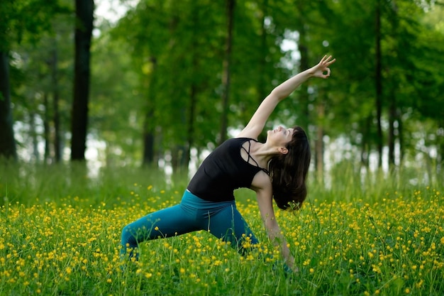 Mujer joven haciendo yoga en un bosque verde