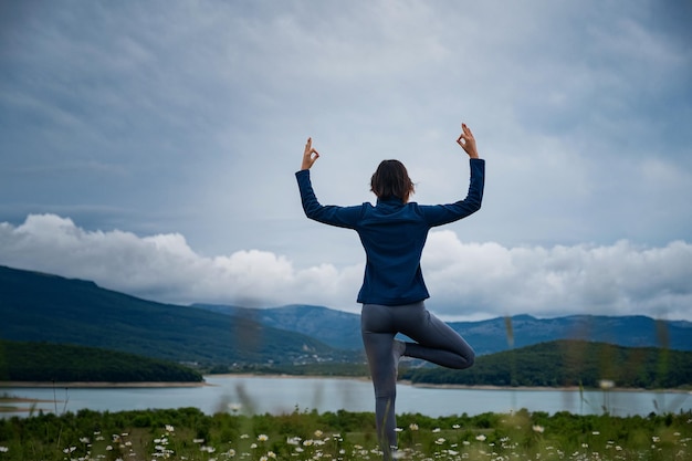 Una mujer joven haciendo yoga en el campo.