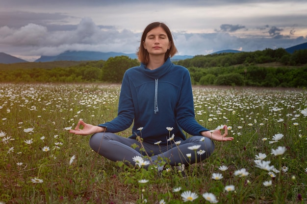 Una mujer joven haciendo yoga en el campo.