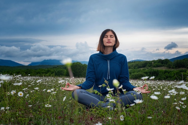 Una mujer joven haciendo yoga en el campo.