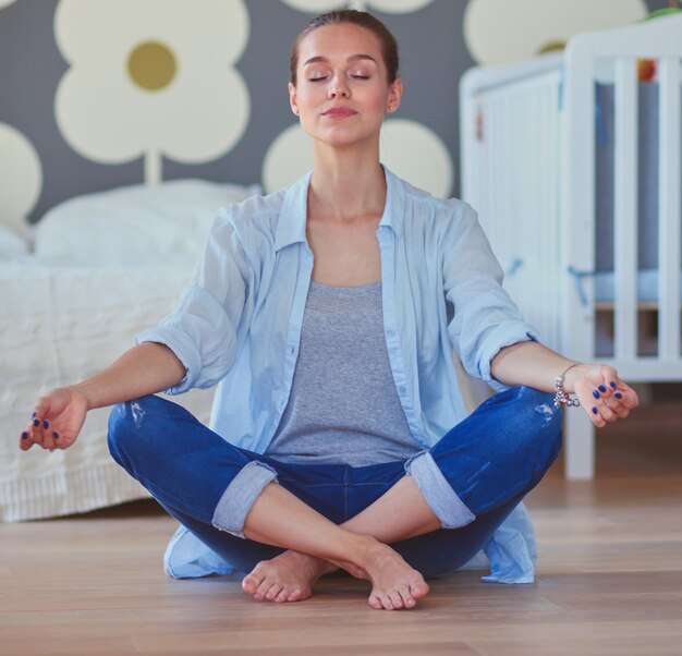 Mujer joven haciendo yoga en casa en posición de loto Mujer joven haciendo yoga