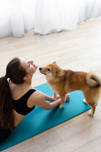 Foto mujer joven haciendo yoga junto a su perro