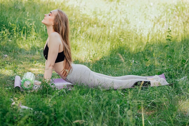 Mujer joven haciendo yoga en el parque de la mañana