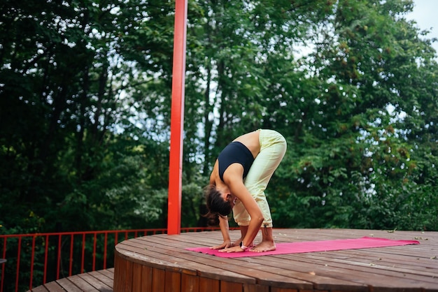 Una mujer joven haciendo yoga en el patio.