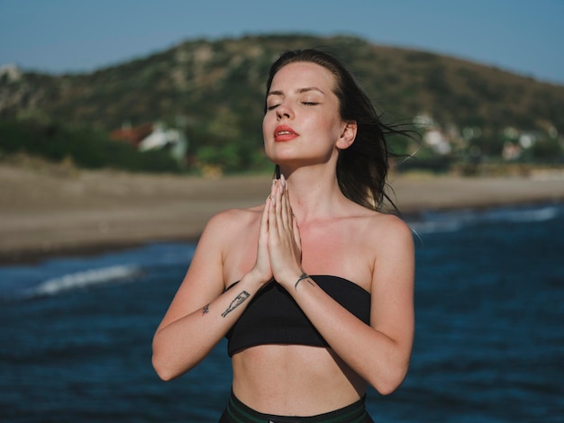 mujer joven haciendo yoga en la playa