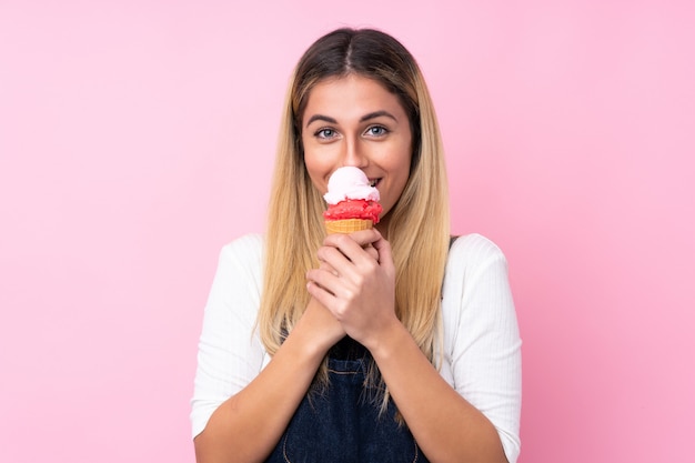 Mujer joven con un helado de cucurucho sobre pared rosa aislado