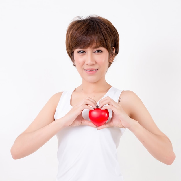 Mujer joven hermosa de Asia con el corazón rojo. Aislado en el fondo blanco Iluminación de estudio. Concepto para la salud.