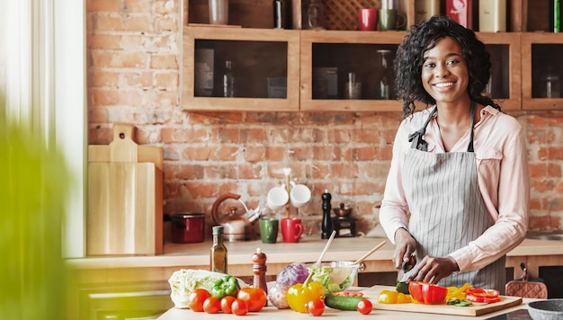 Mujer joven y hermosa cocinando ensalada saludable en la cocina