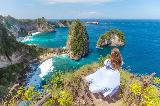 Mujer joven en la hermosa costa de roca en mil islas en la isla de Nusa Penida